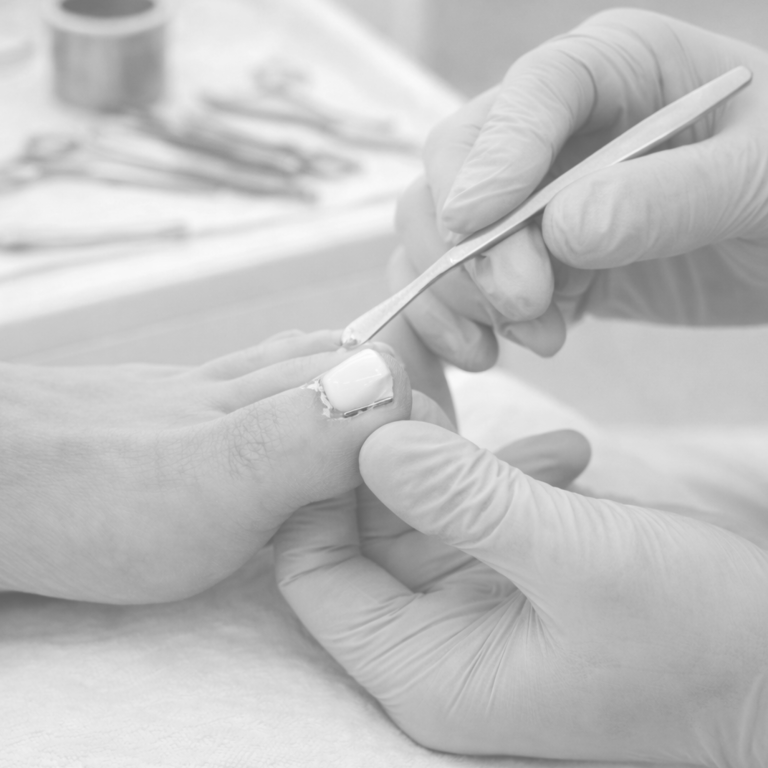 Mani- oder Pediküre: Eine Hand behandelt den großen Zeh mit einem Instrument.