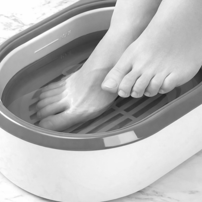 Füße in einem Fußbad mit Wasser und einem grauen Rand.