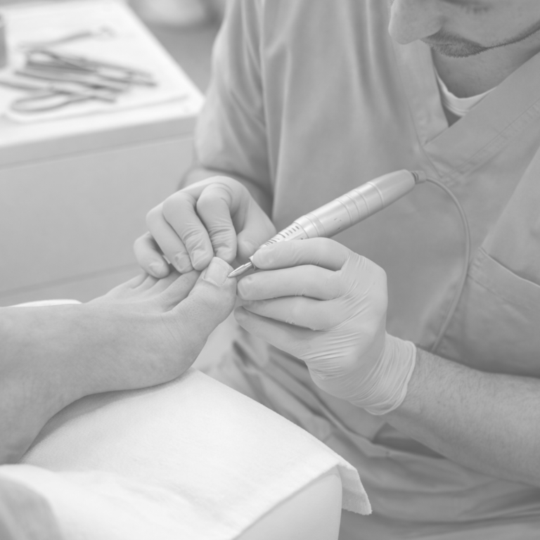 Fusspflege: Person schneidet Nägel mit einem elektrischen Werkzeug.